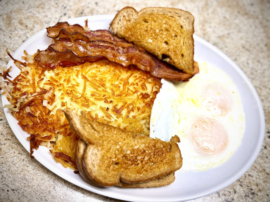 Breakfast plate with eggs, bacon, hash browns, and toast