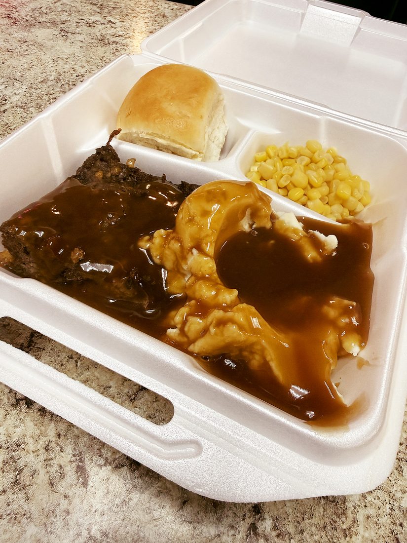 Meatloaf with mashed potatoes, gravy, corn, and a roll